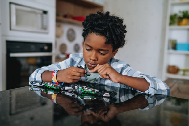 A close-up of a child playing with toy cars flipped upside down